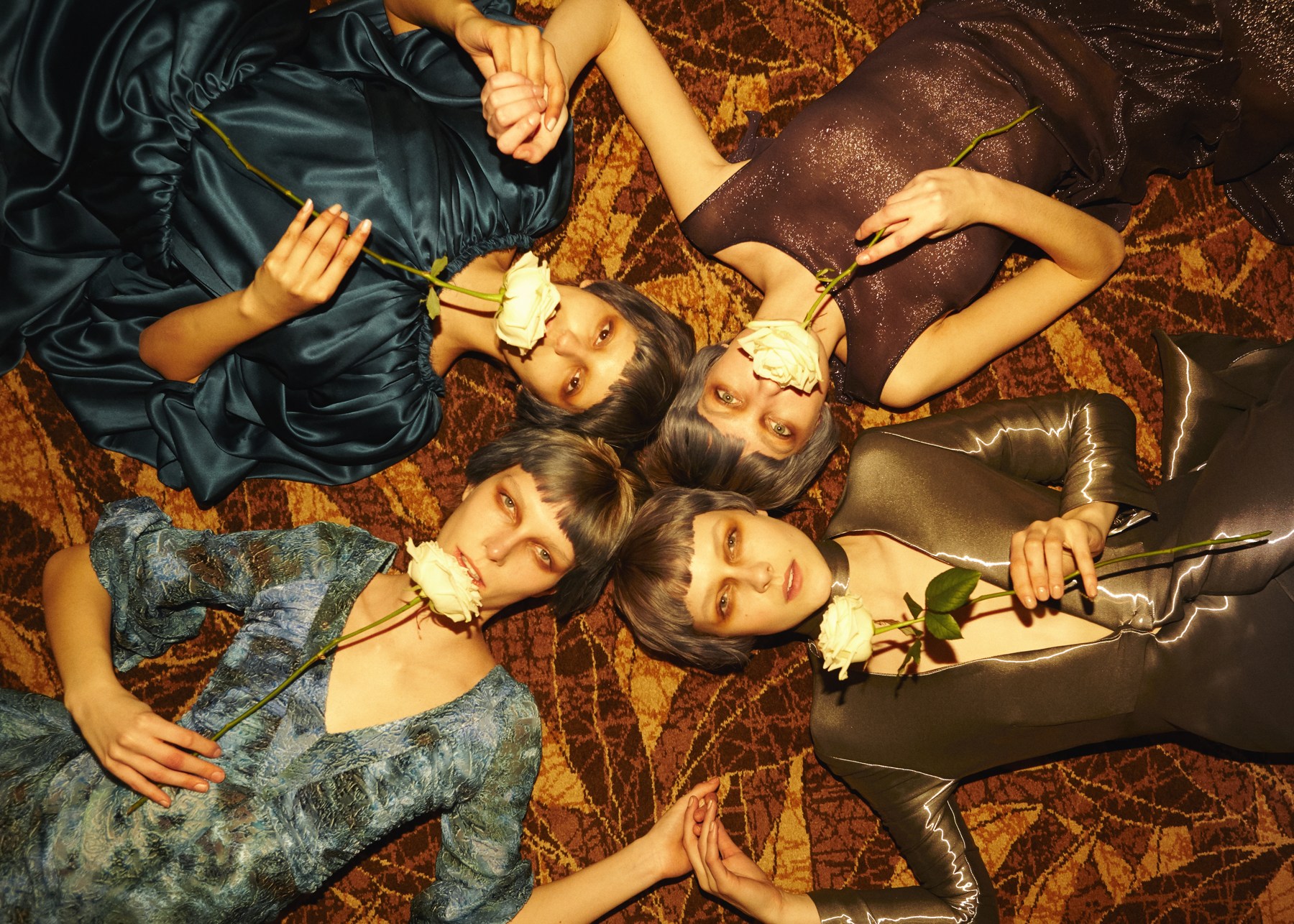 Overhead portrait of models holding flowers, wearing jewel-coloured velvet and metallic looks from Tsarina