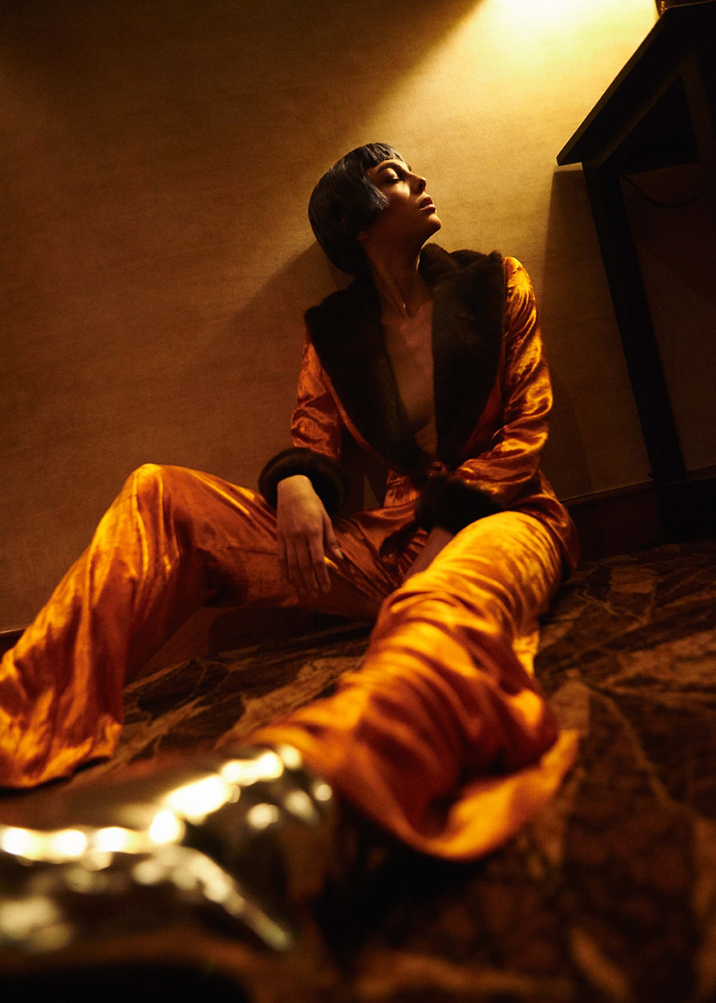 Gold velvet and metallic boots photographed from below in warm amber light